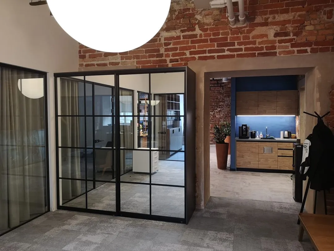 Office entrance with black-framed glass partitions and kitchenette