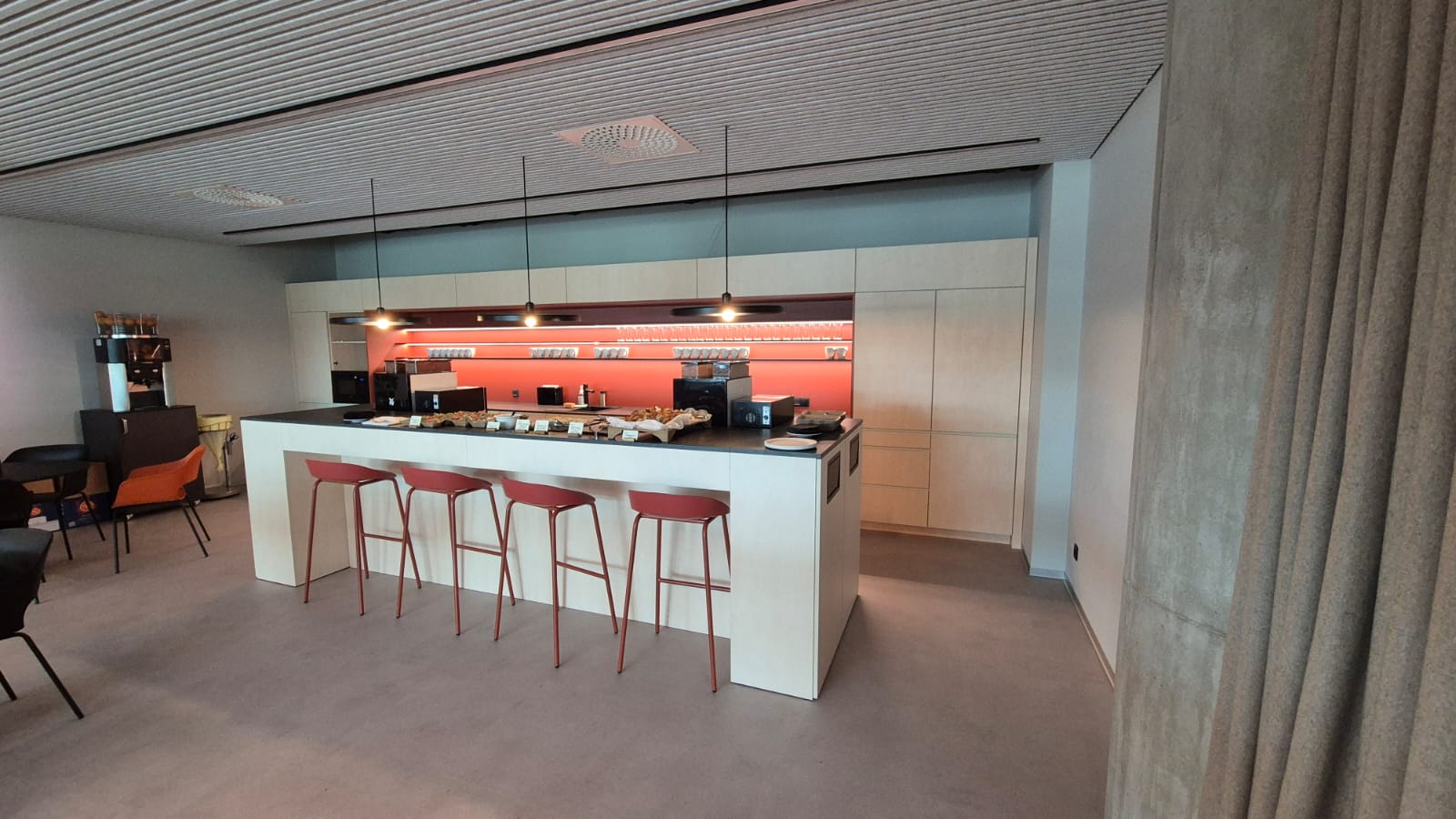 Office kitchen with white island and red bar stools