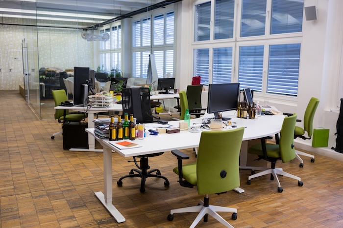Open-plan office with desks and green chairs