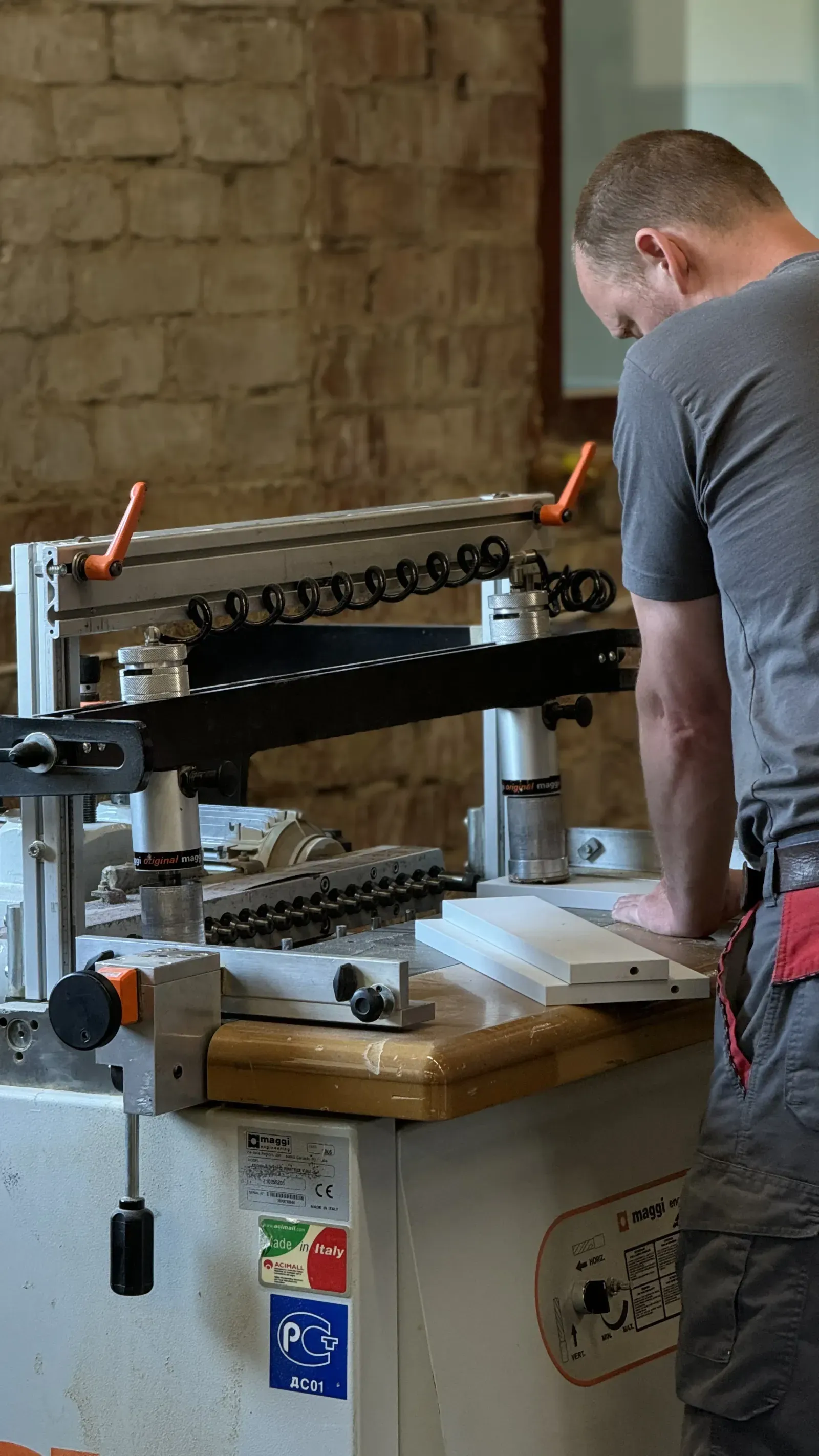 Worker operating a drilling machine in the workshop