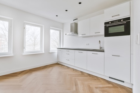 White fitted kitchen with herringbone wood floor